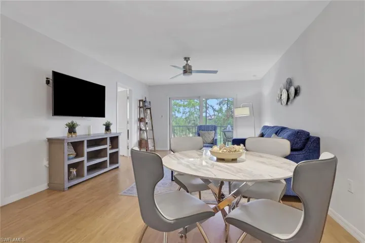 Open-concept living area with wood-finish flooring, a contemporary ceiling fan, and sliding glass doors providing natural light