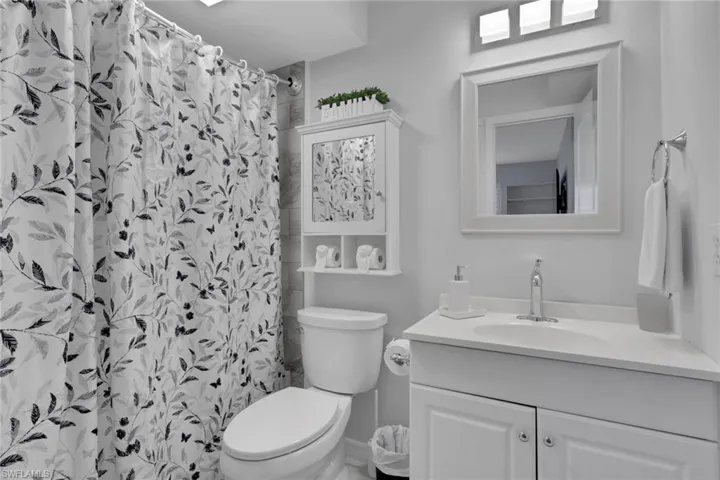 Bathroom featuring a white vanity with a single sink, white framed mirror, and a three-light fixture