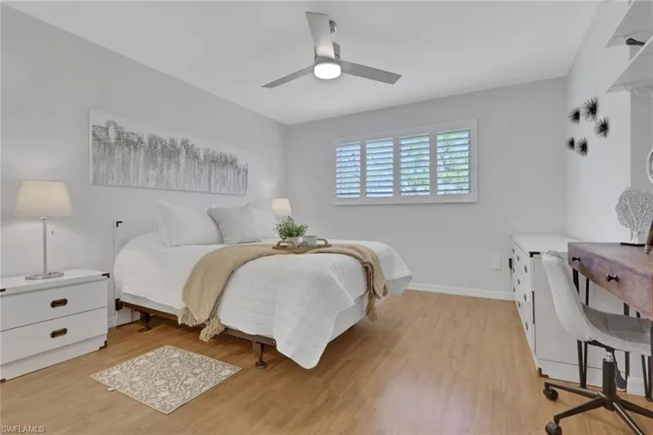 Bright interior space featuring wood-finish flooring, a contemporary ceiling fan with integrated lighting, and white plantation shutters