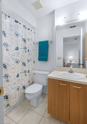 Full bath with vanity, light tile patterned floors, and curtained shower