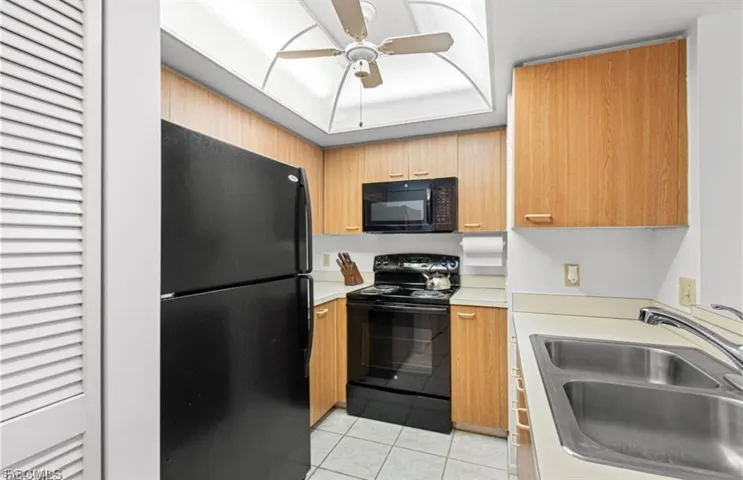 Kitchen featuring black appliances, light tile patterned floors, light countertops, and a ceiling fan