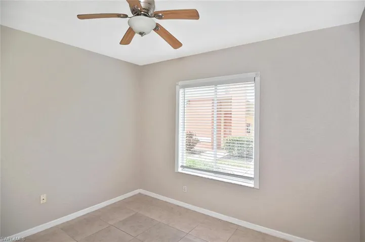 Empty room with ceiling fan and light tile patterned floors