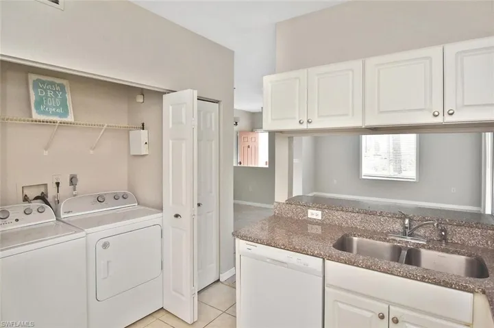 Laundry area with light tile patterned flooring and independent washer and dryer