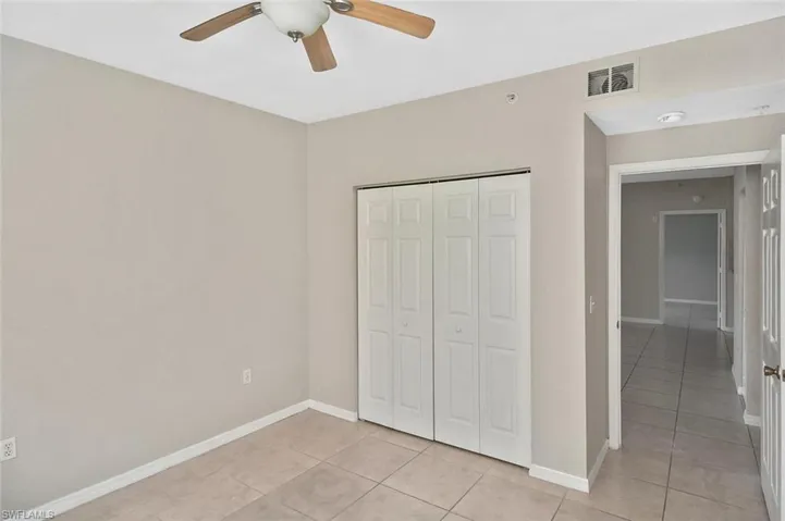 Unfurnished bedroom with a closet, light tile patterned flooring, and a ceiling fan