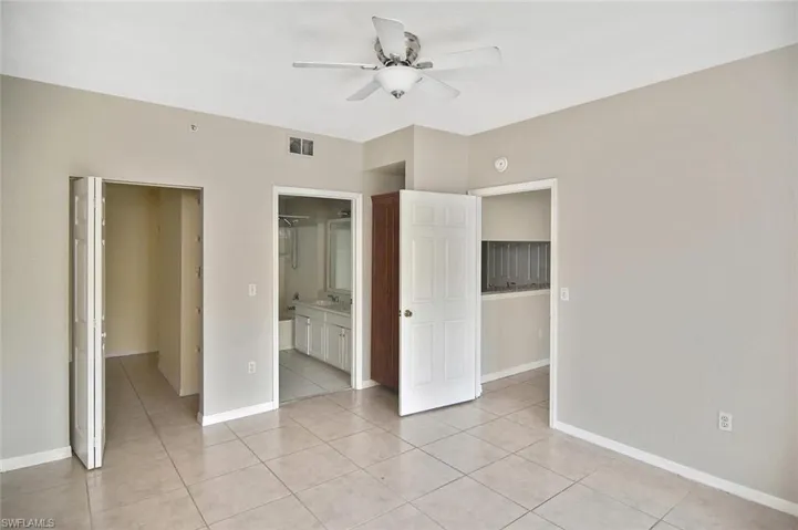 Unfurnished bedroom featuring light tile patterned floors, ceiling fan, and ensuite bathroom