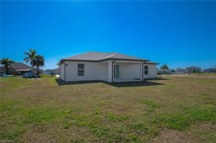 Back of house featuring a lawn and stucco siding