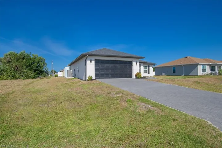View of front of home featuring driveway, a front yard, stucco siding, and an attached garage
