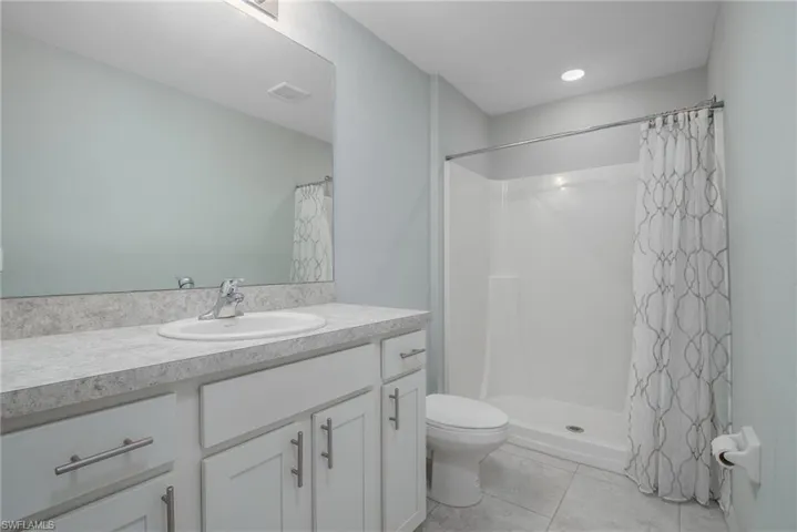 Bathroom with a shower with curtain, vanity, toilet, visible vents, and tile patterned flooring