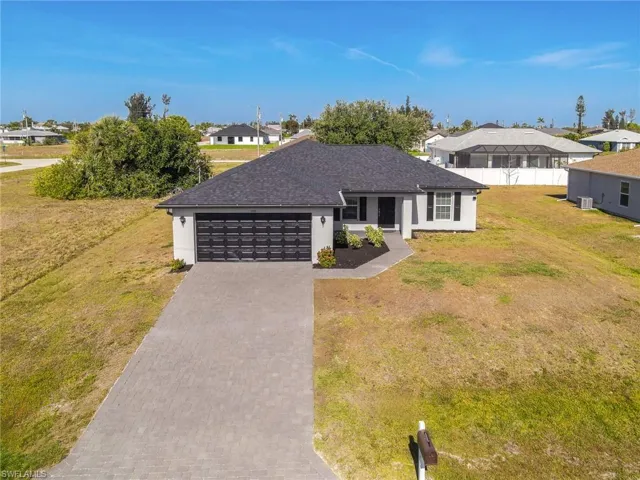 Ranch-style home featuring stucco siding, decorative driveway, a residential view, a front lawn, and an attached garage