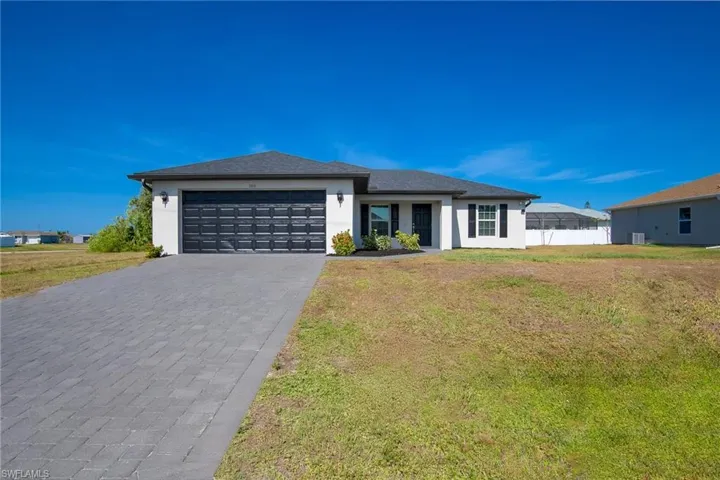 Prairie-style house with stucco siding, decorative driveway, a front lawn, and an attached garage