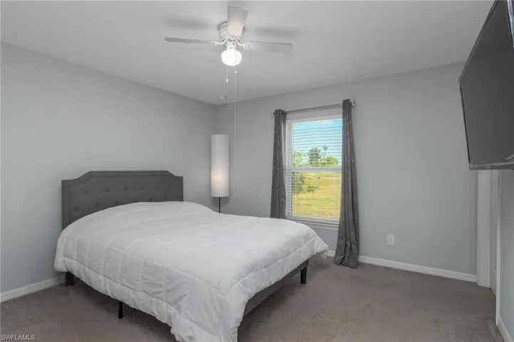 Carpeted bedroom with baseboards and a ceiling fan