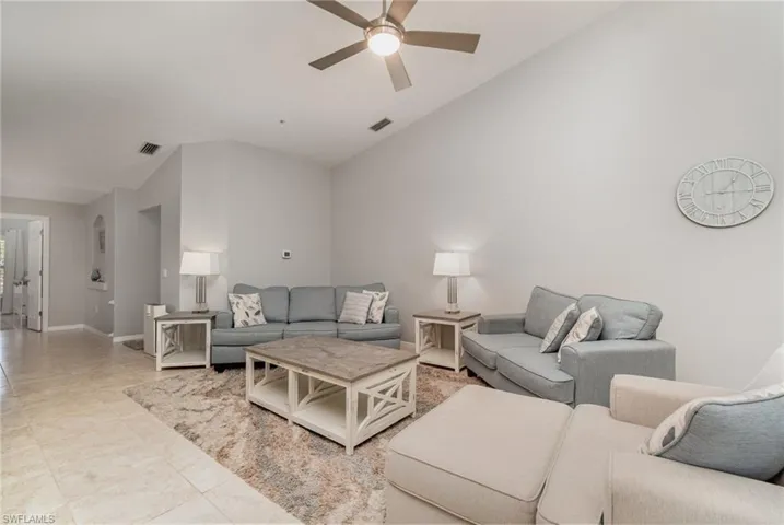 Living room featuring lofted ceiling, a ceiling fan, and baseboards