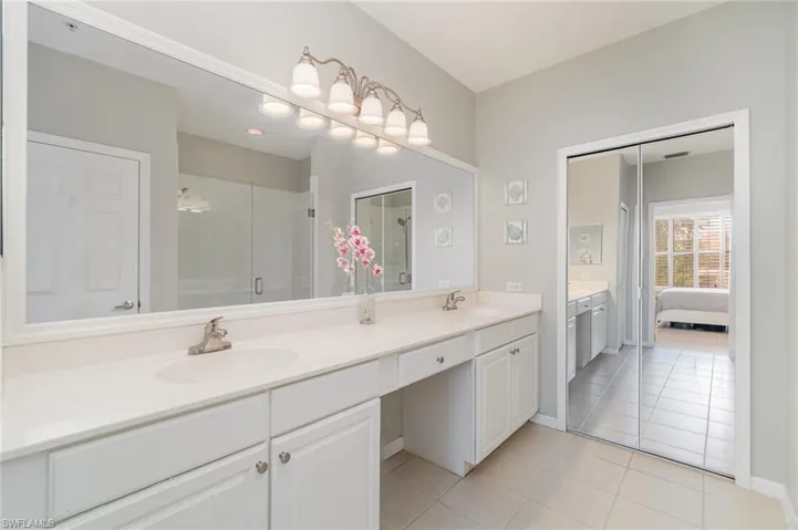 Ensuite bathroom with double vanity, tile patterned floors, and a stall shower