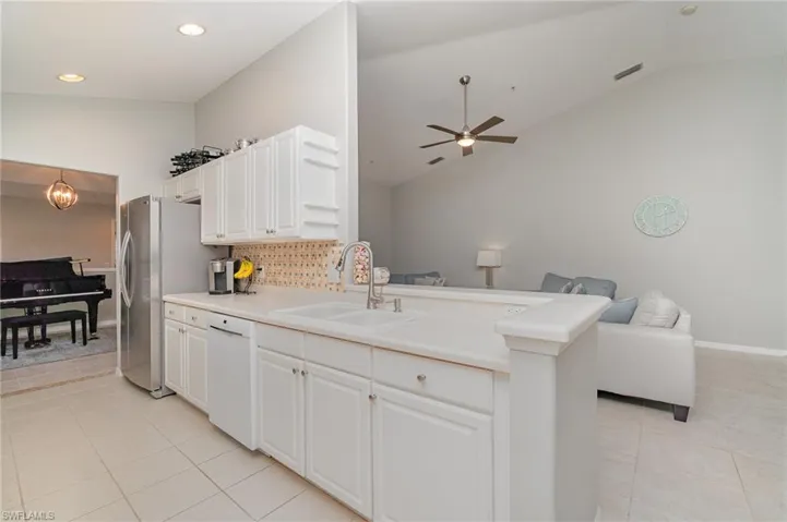Kitchen featuring a sink, dishwasher, open floor plan, light tile patterned floors, and tasteful backsplash
