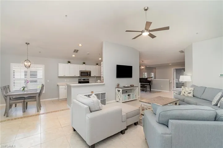 Living room with light tile patterned floors, a ceiling fan, baseboards, lofted ceiling, and recessed lighting