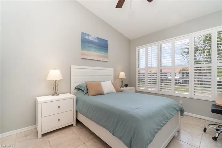 Bedroom featuring vaulted ceiling, multiple windows, baseboards, and light tile patterned flooring