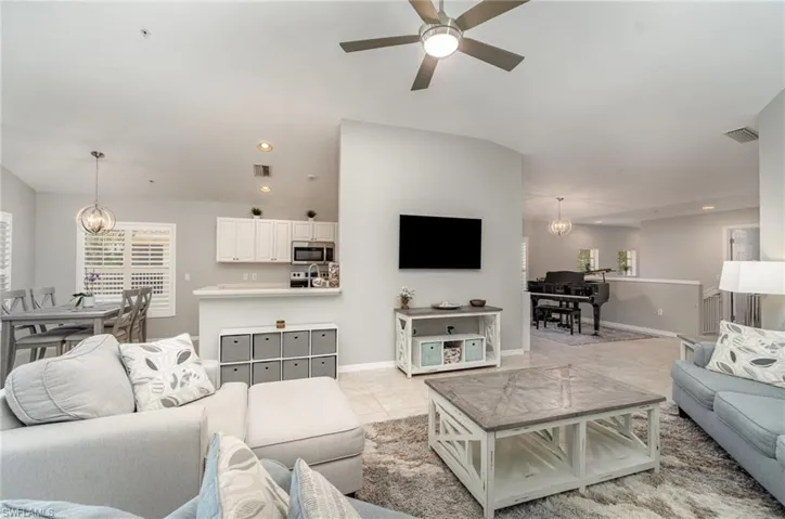 Living area with a chandelier, a ceiling fan, recessed lighting, light tile patterned floors, and baseboards