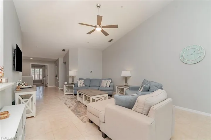 Living area featuring a ceiling fan, high vaulted ceiling, baseboards, and light tile patterned floors