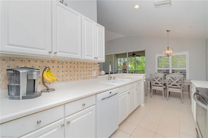 Kitchen featuring dishwasher, a sink, electric stove, vaulted ceiling, and light tile patterned floors