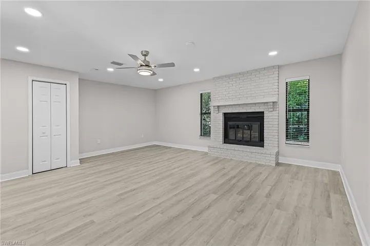 Unfurnished living room featuring a fireplace, ceiling fan, and light hardwood / wood-style flooring