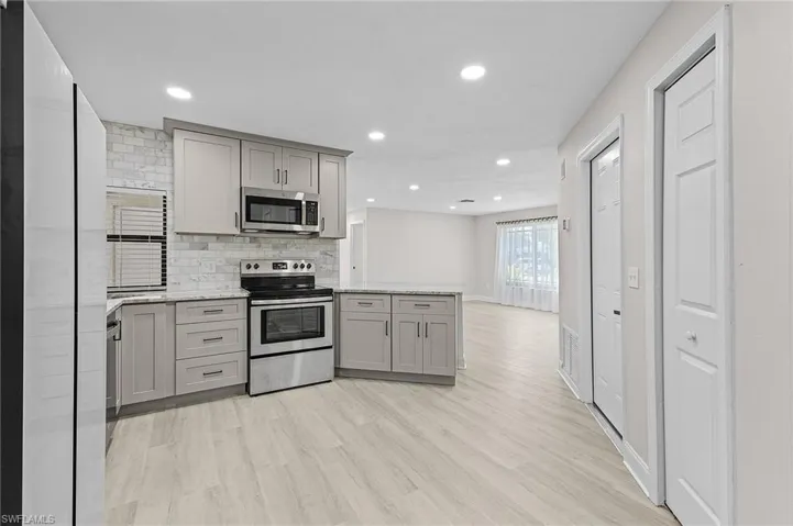 Kitchen featuring backsplash, gray cabinets, light hardwood / wood-style flooring, and appliances with stainless steel finishes
