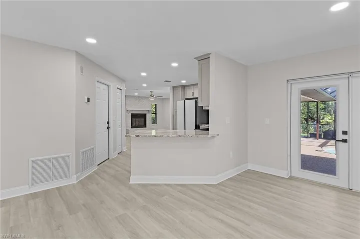 Kitchen with light stone countertops, a brick fireplace, kitchen peninsula, and light hardwood / wood-style flooring