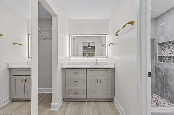 Bathroom featuring hardwood / wood-style flooring, vanity, and a tile shower