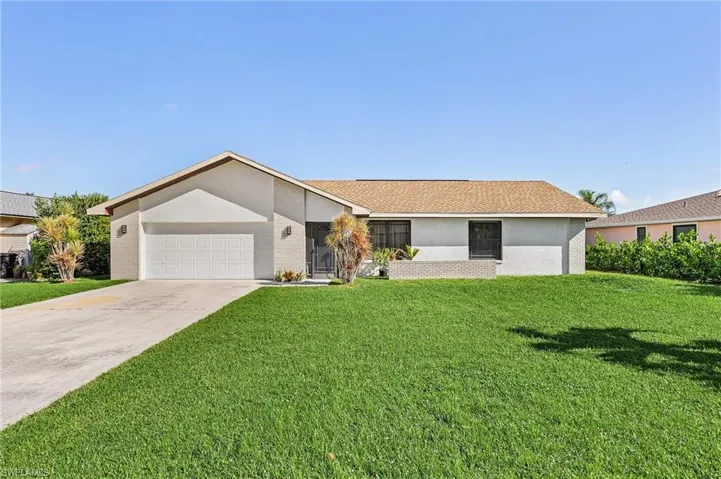 Ranch-style house featuring a garage and a front lawn