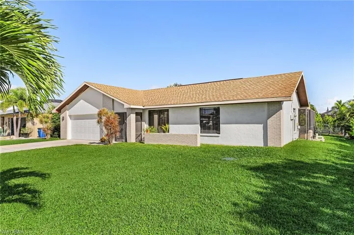 Ranch-style home featuring a front yard and a garage