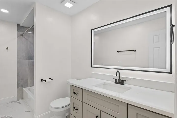 Full bathroom featuring vanity, tiled shower / bath combo, and toilet
