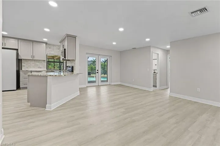 Kitchen featuring gray cabinets, light stone counters, light wood-type flooring, and white refrigerator