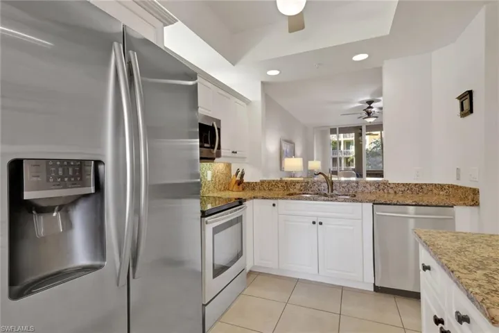 Kitchen with stainless steel appliances, recessed lighting, white cabinets, dark stone counters, and light tile patterned flooring