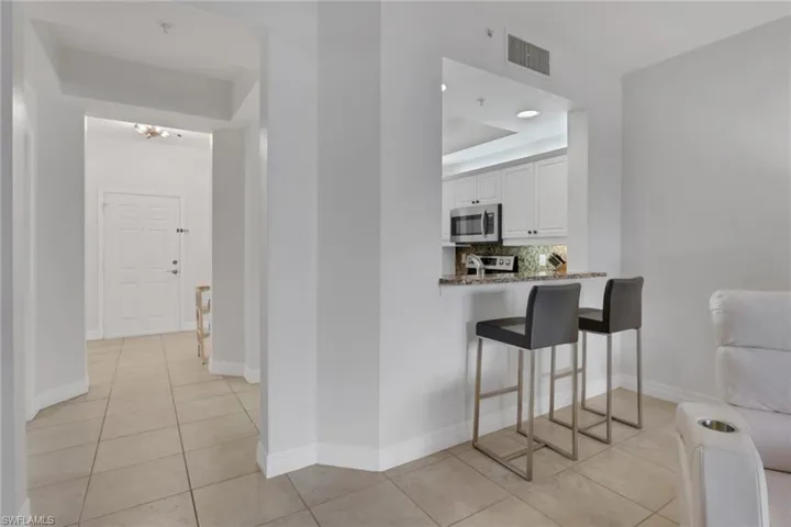 Hall featuring light tile patterned flooring and a tray ceiling
