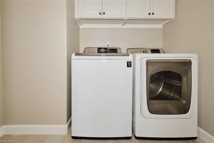 Laundry area with cabinet space, washing machine and dryer, and light wood-type flooring