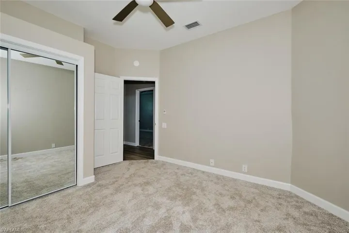 Unfurnished bedroom featuring light colored carpet, ceiling fan, and a closet