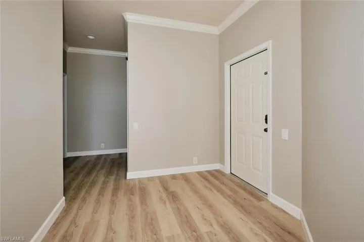 Entrance foyer with ornamental molding, light wood finished floors, and recessed lighting