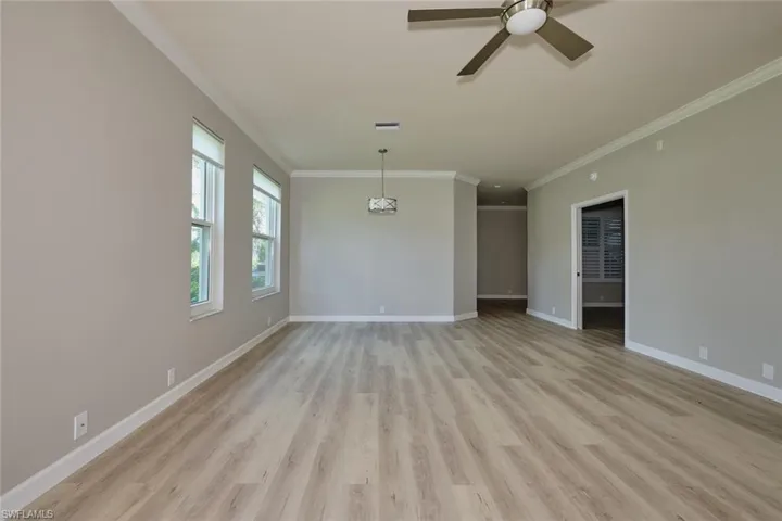 Empty room with light wood finished floors, crown molding, and ceiling fan