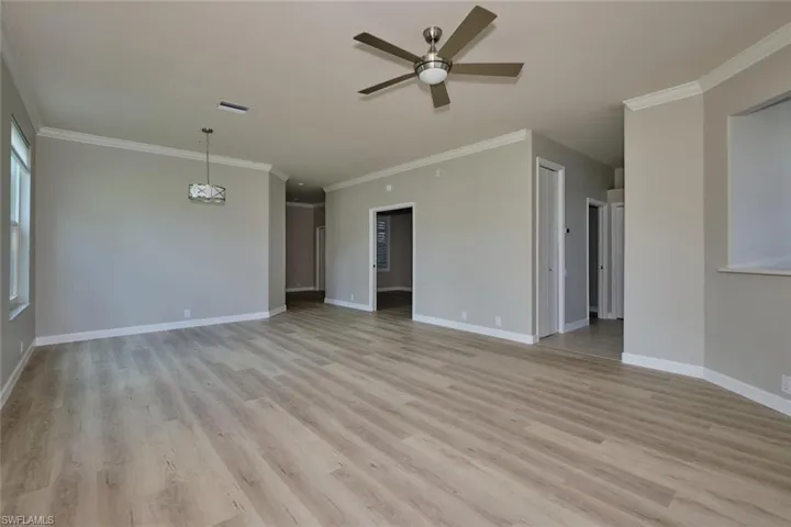 Unfurnished living room with crown molding, light wood finished floors, and a ceiling fan