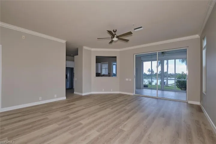 Spare room featuring light wood-style flooring, ceiling fan, and crown molding