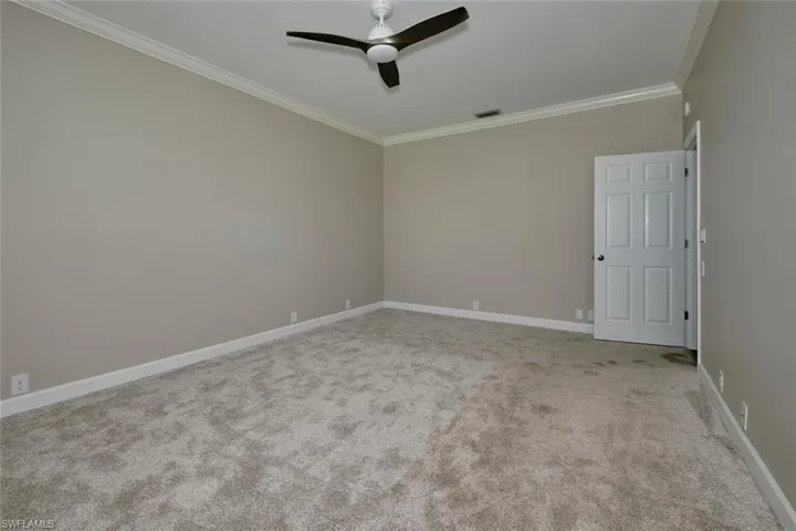 Empty room featuring ornamental molding, light colored carpet, and ceiling fan