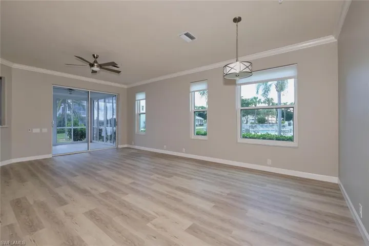 Unfurnished room featuring ornamental molding, light wood finished floors, healthy amount of natural light, and ceiling fan