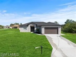 View of front facade featuring a front yard, an attached garage, and concrete driveway