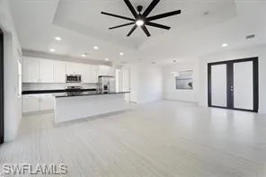 Kitchen with open floor plan, dark countertops, french doors, white cabinetry, and recessed lighting