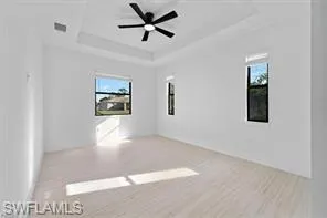 Unfurnished room featuring a ceiling fan and a tray ceiling