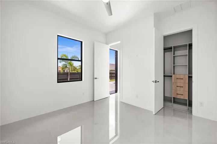 Bright room featuring a black-framed window, sleek reflective flooring, and a modern ceiling fan