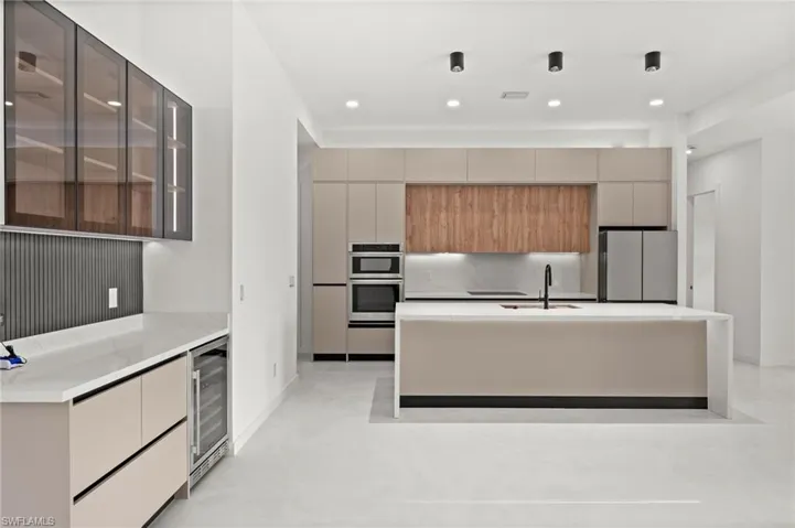 Modern kitchen featuring a large central island with an integrated sink and black faucet