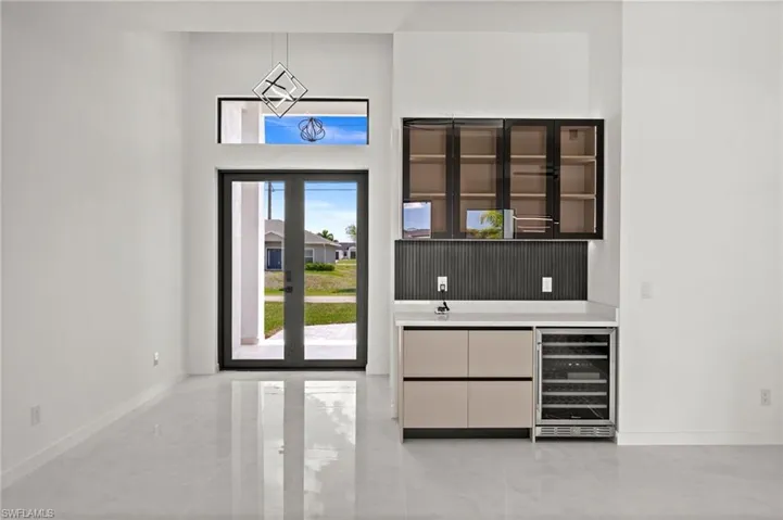 Entry foyer featuring double glass-panel doors, transom window, and a modern geometric pendant light
