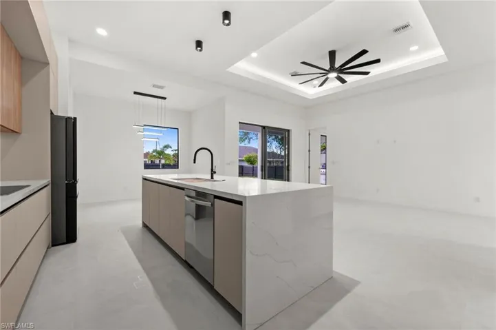 Modern kitchen featuring a large waterfall-edge island with an integrated dishwasher, a black gooseneck faucet, and quartz countertops