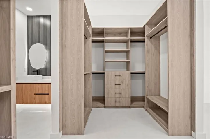 Spacious walk-in closet featuring extensive built-in shelving, hanging rods, and integrated drawer storage