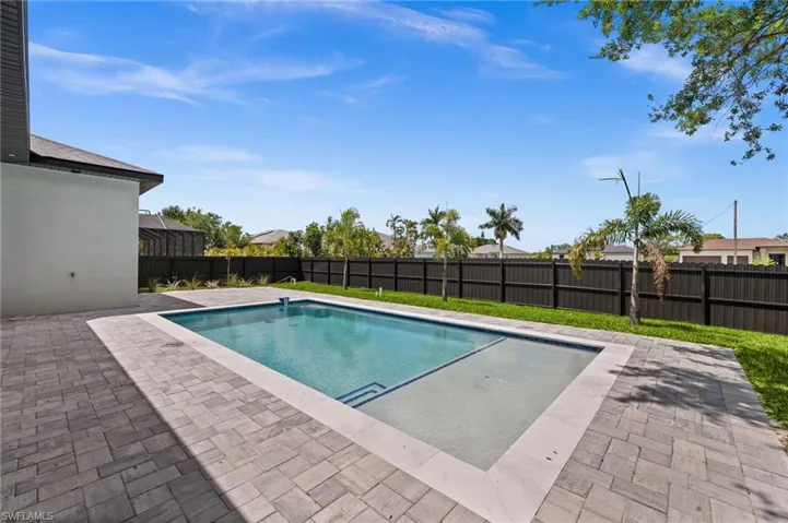 Private backyard oasis featuring a rectangular swimming pool with integrated steps, surrounded by extensive paver decking